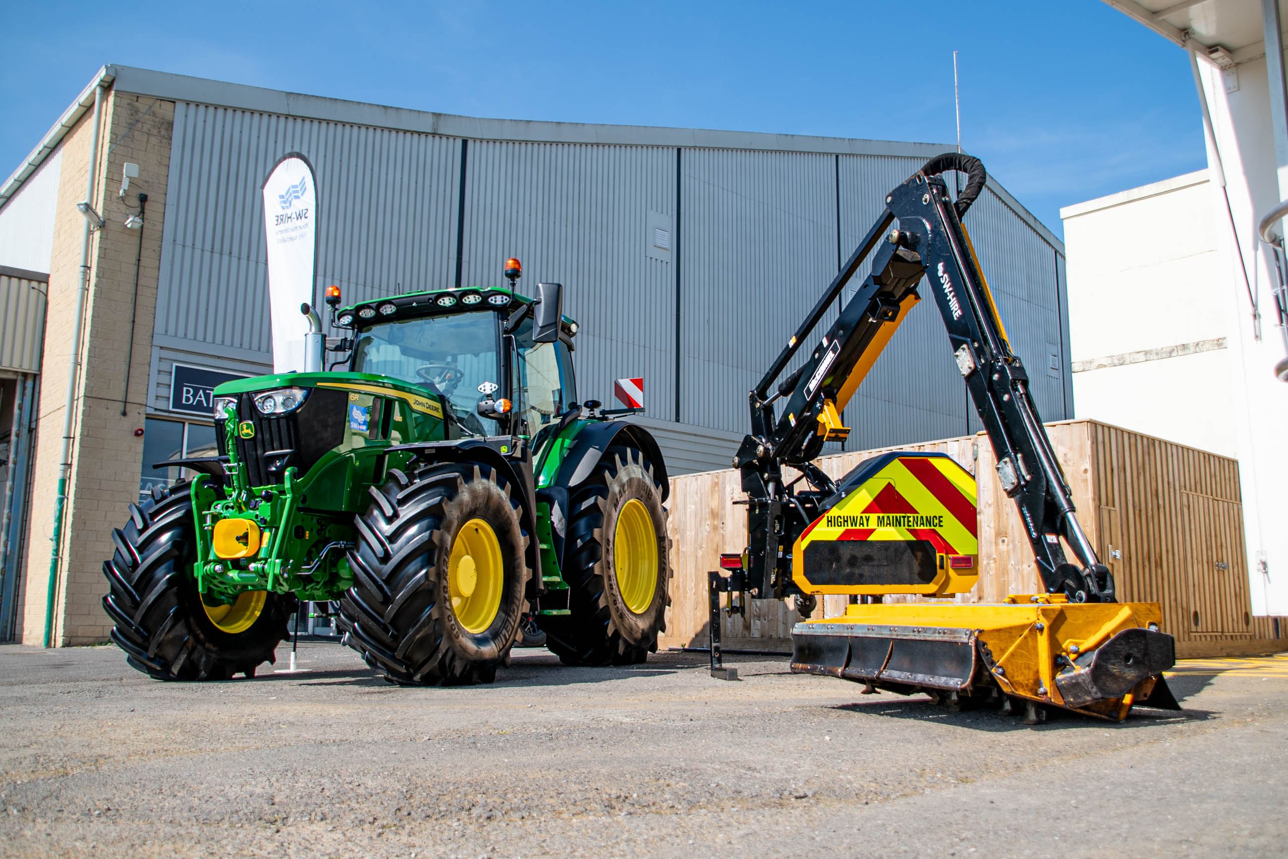 John Deere 6R 215 with chrome exhaust in front of Bath & West Showground building next to McConnel PA6567T